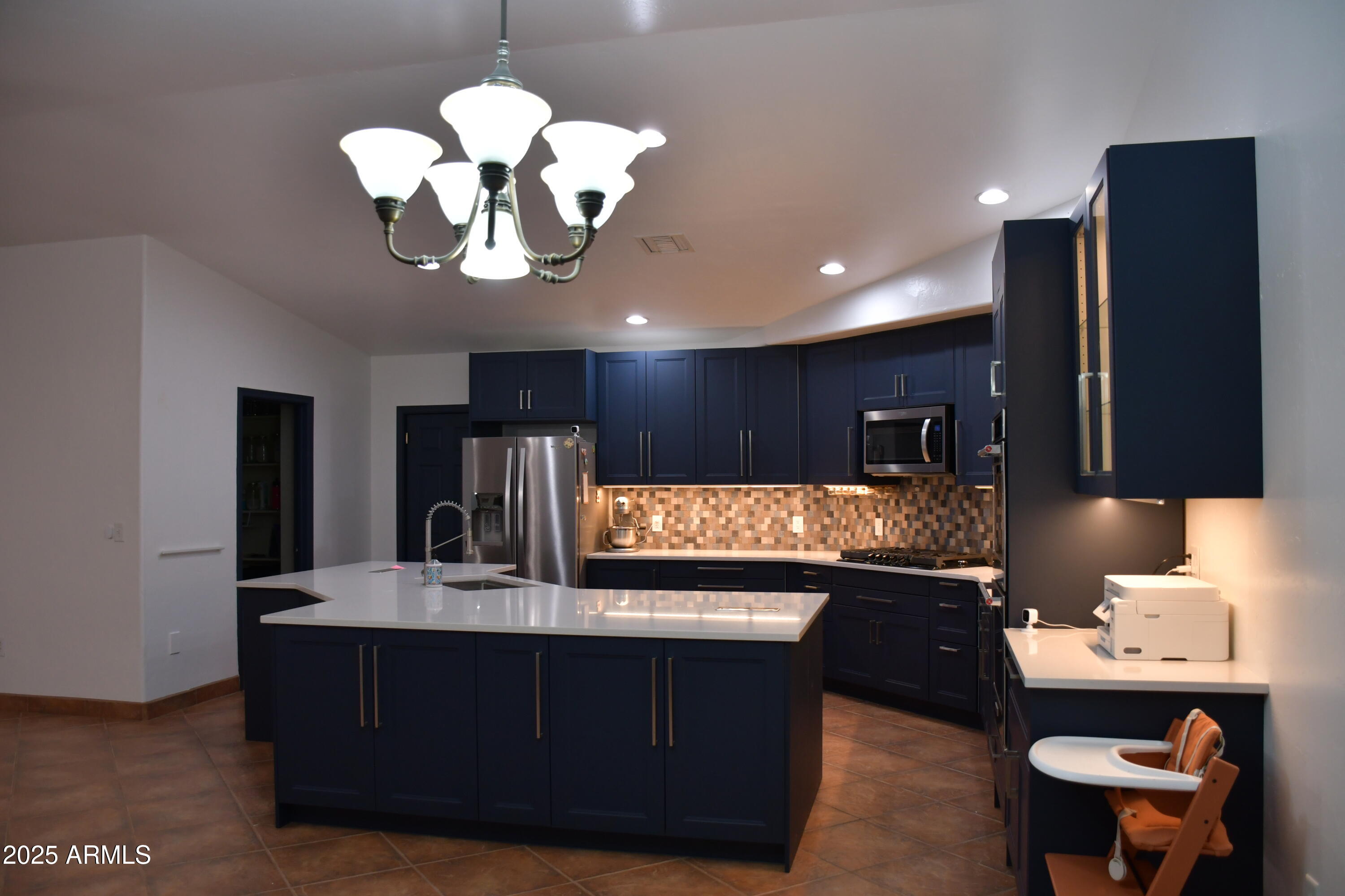 3298 West Monte Vista Trail Benson, AZ 85602 - Photo 12 of 44 a kitchen with a chandelier stainless steel appliances a sink and a refrigerator