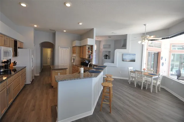 a kitchen with stainless steel appliances granite countertop a refrigerator sink and white cabinets