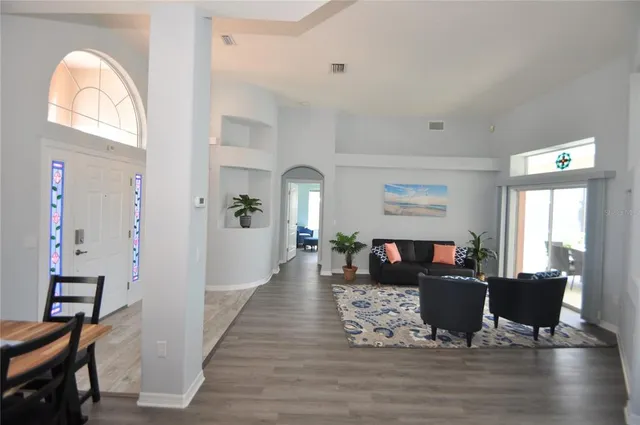 a view of a dining room with furniture a chandelier and large windows