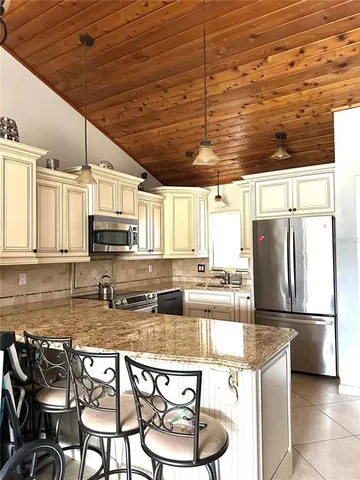 a kitchen with stainless steel appliances kitchen island granite countertop a sink a stove and a wooden floors