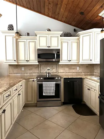 a kitchen with stainless steel appliances granite countertop a refrigerator a sink a stove a microwave and wooden cabinets