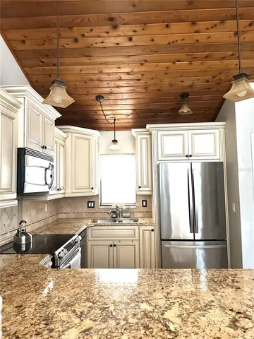 a kitchen with stainless steel appliances granite countertop a sink a stove and a wooden cabinets