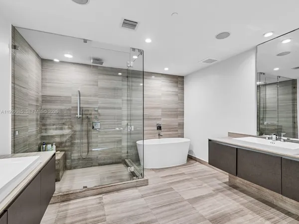 a bathroom with a bathtub shower sink mirror and toilet