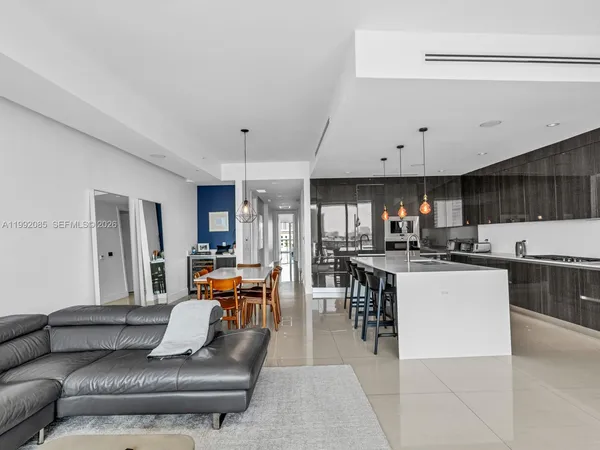 a living room with furniture kitchen view and a large window