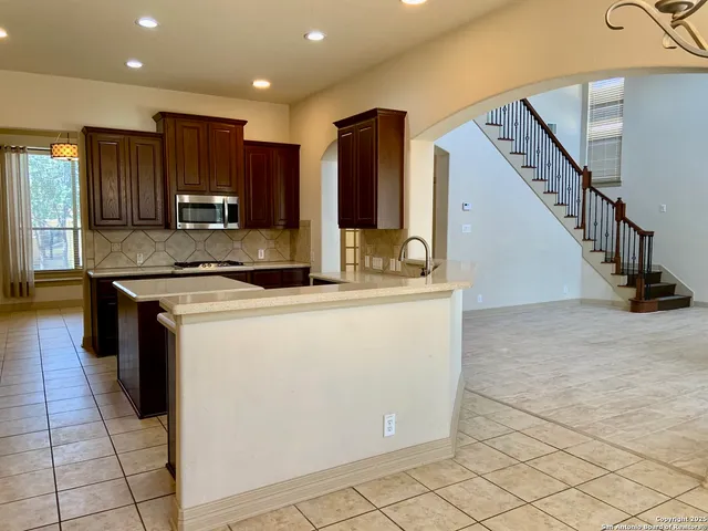 a kitchen with kitchen island granite countertop a stove a sink and a microwave