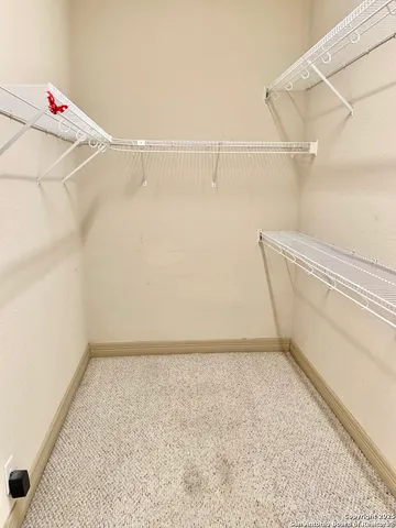 an empty room with chandelier fan and windows