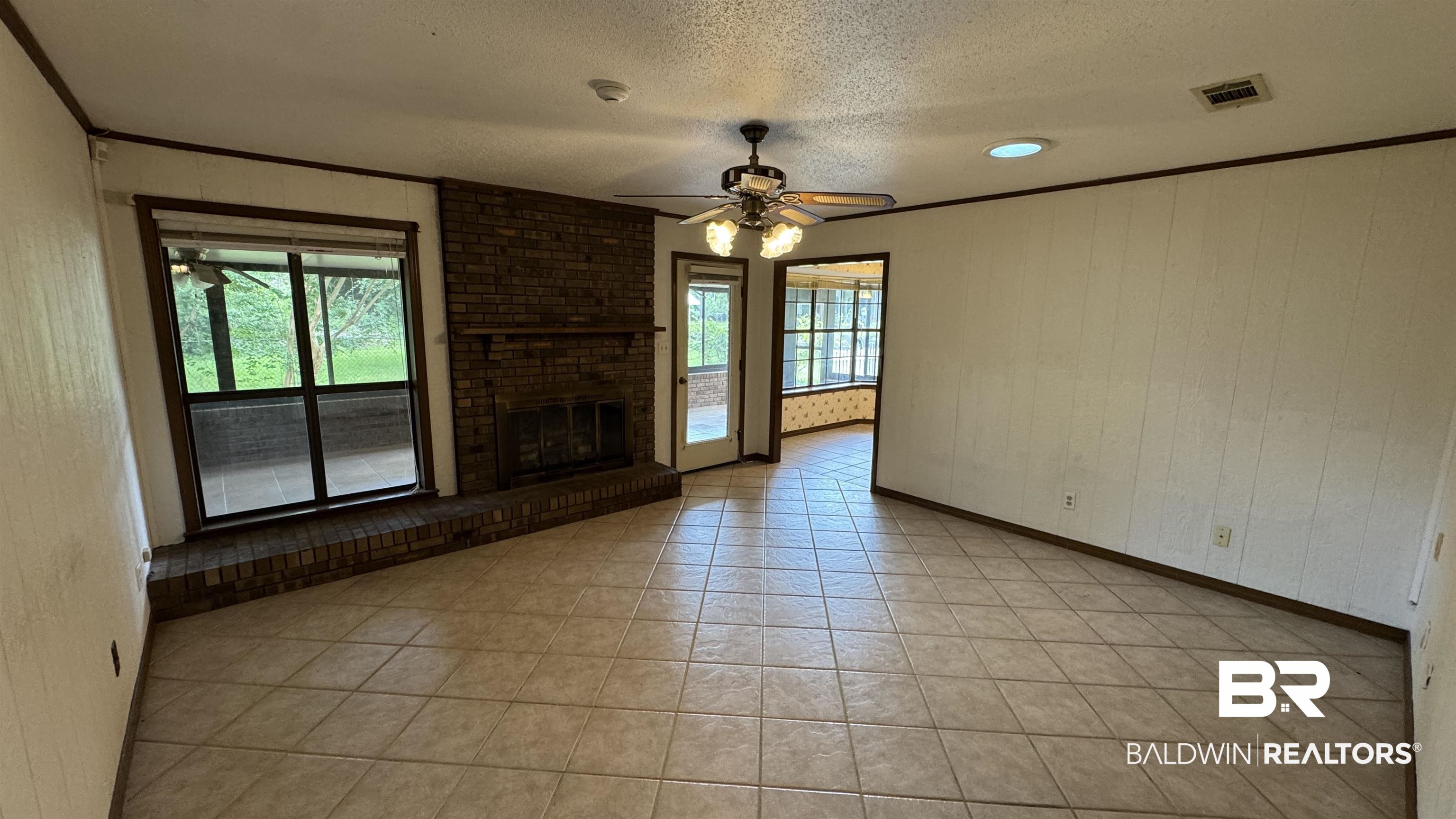 33370 Highway 98 Lillian, AL 36549 - Photo 25 of 58 Spacious room featuring tile flooring, a brick fireplace with a hearth, and a ceiling fan with integrated lighting