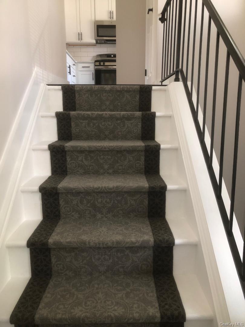 85 North Middletown Road, Unit D10 Nanuet, NY 10954 - Photo 2 of 12 Staircase featuring a patterned carpet runner and white risers