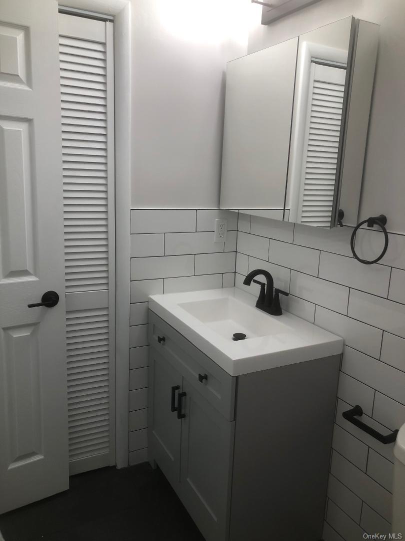 85 North Middletown Road, Unit D10 Nanuet, NY 10954 - Photo 8 of 12 Pretty updated bathroom which features a vanity featuring a light gray shaker-style cabinet, integrated sink, and matte black hardware