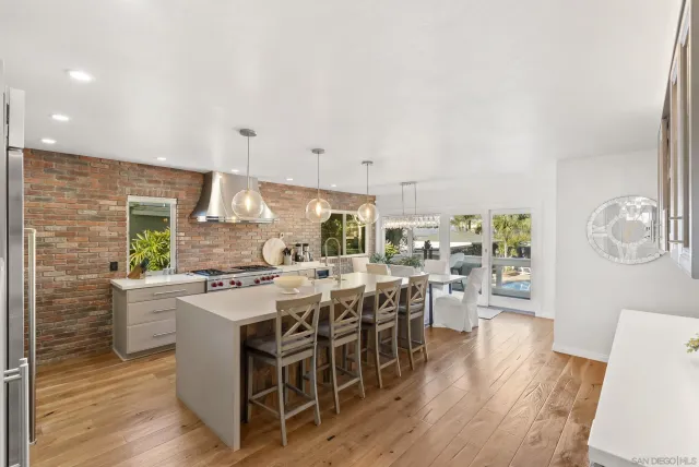 a kitchen with stainless steel appliances a stove a sink dishwasher and a dining table with wooden floor