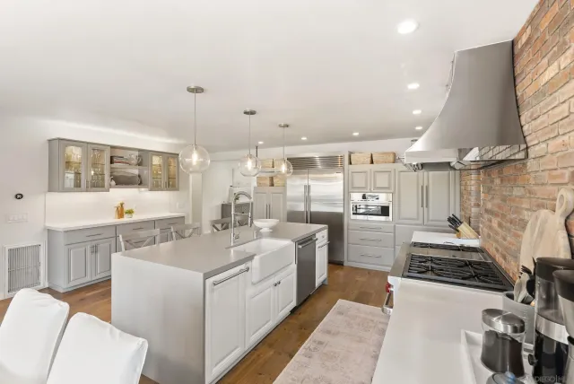 a large white kitchen with sink and stainless steel appliances
