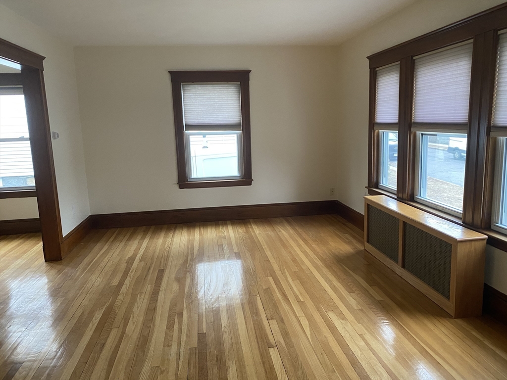 19-21 Virgil Road, Unit 1 Boston, MA 02132 - Photo 4 of 13 an empty room with wooden floor and windows