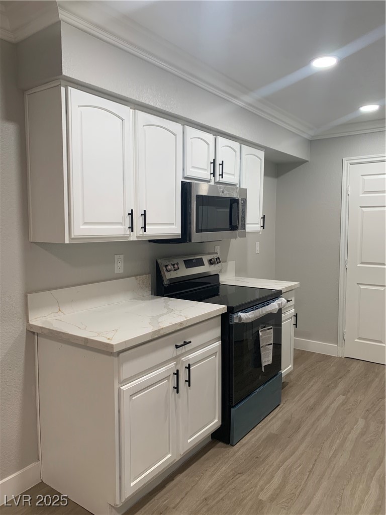 8101 West Flamingo Road, Unit 1102 Las Vegas, NV 89147 - Photo 23 of 54 Kitchen featuring range with electric cooktop, light wood-type flooring, ornamental molding, light stone countertops, and white cabinets