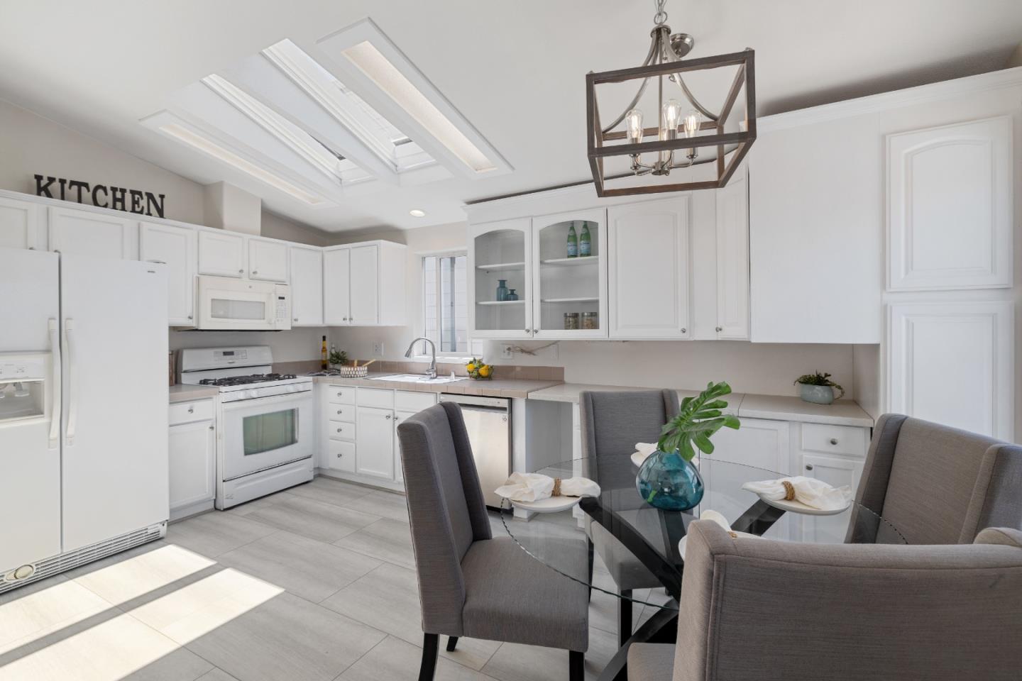 14685 Oka Road, Unit 62 Los Gatos, CA 95032 - Photo 7 of 27 a white kitchen with stainless steel appliances a white table chairs and a refrigerator