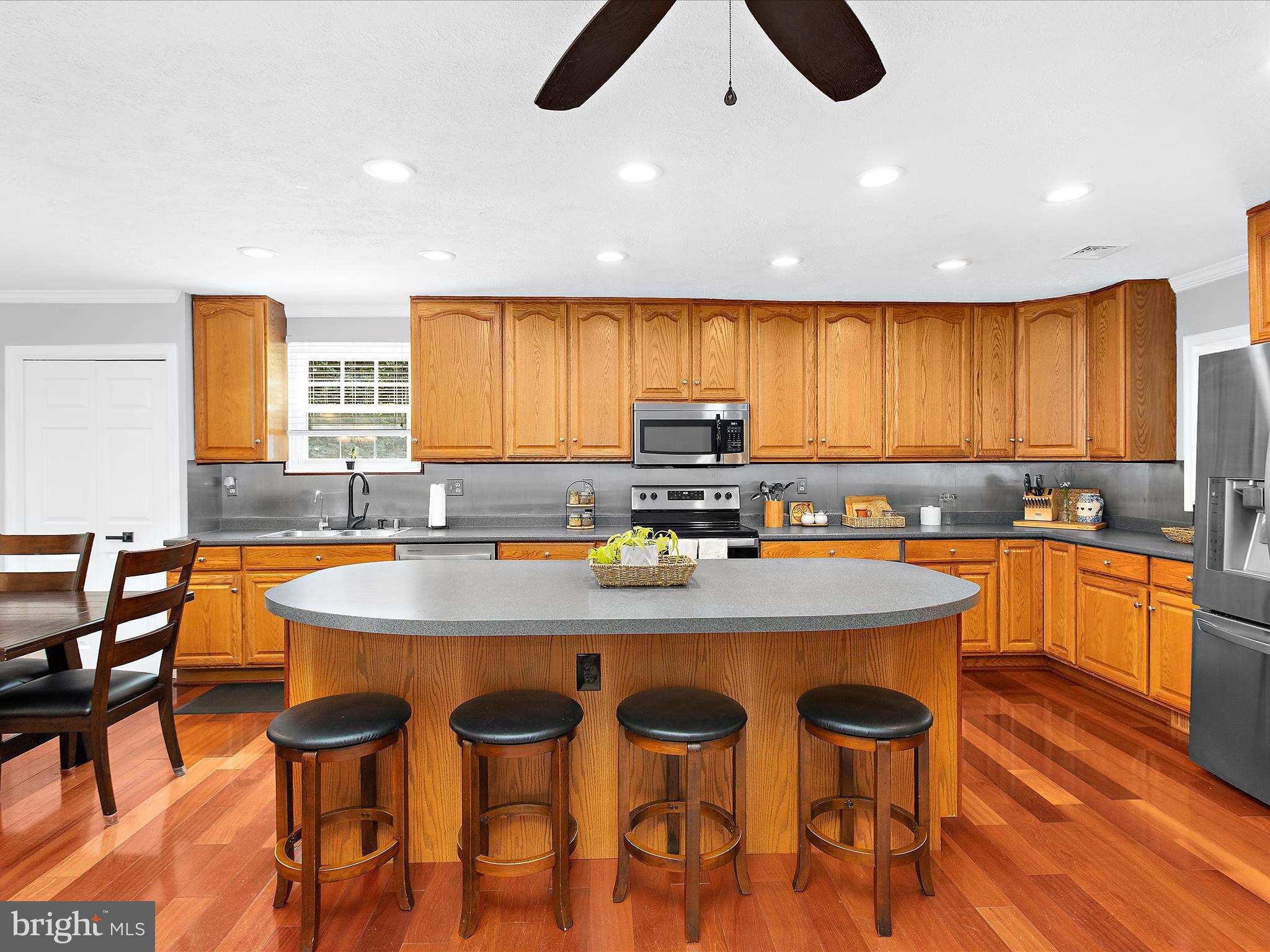 1217 Somerset Road Severn, MD 21144 - Photo 6 of 86 a kitchen with stainless steel appliances granite countertop a stove a sink a microwave a dining table and chairs with wooden floor