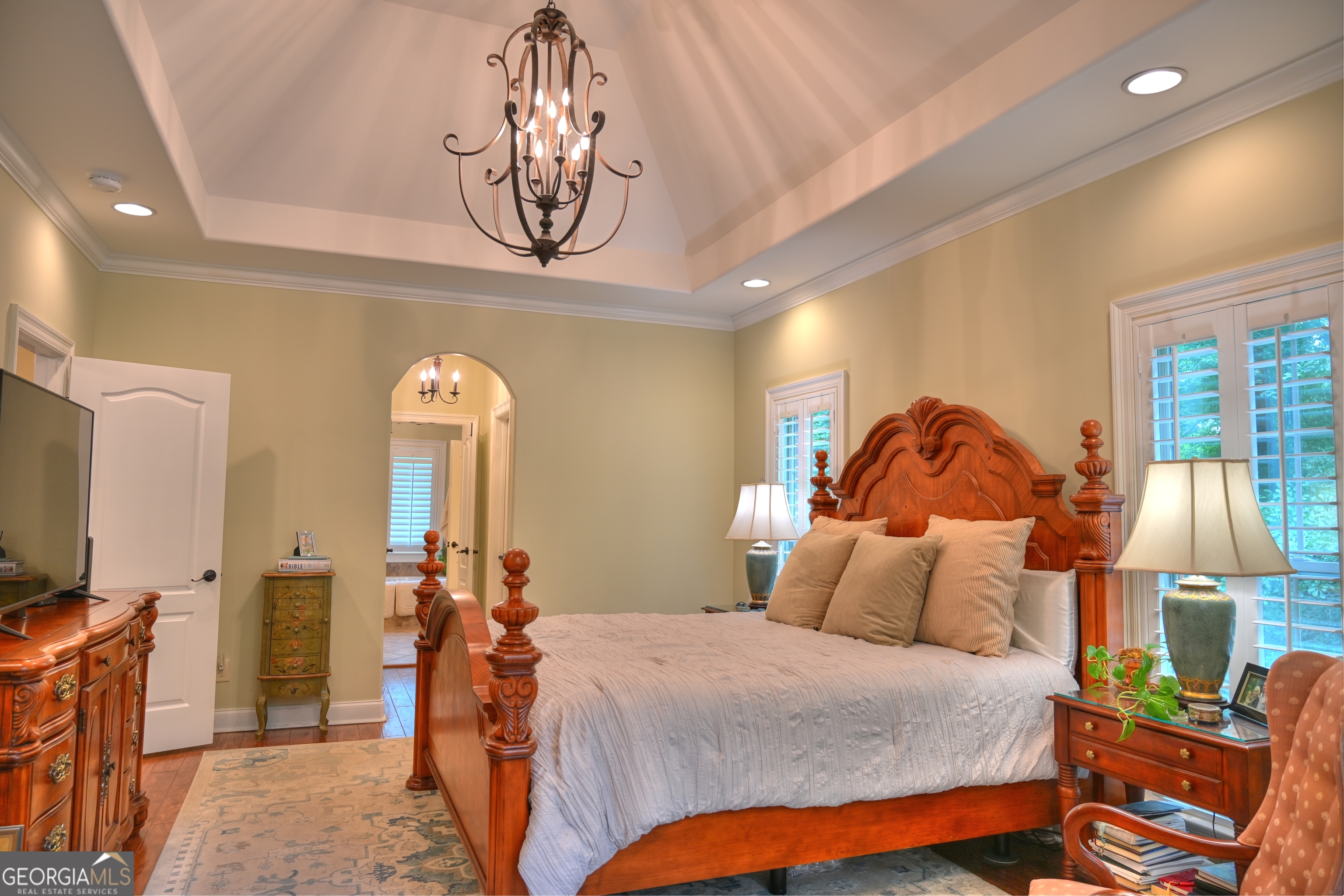 7381 Lullwater Road Columbus, GA 31904 - Photo 3 of 47 a bedroom with a bed a mirror on the dresser and a chandelier