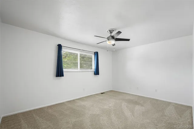 an empty room with window and ceiling fan