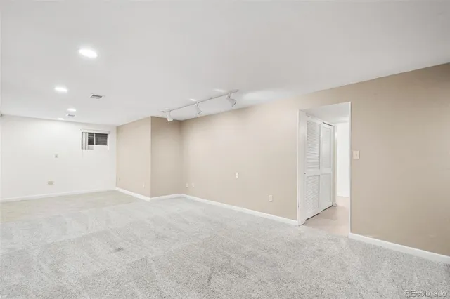 an empty room with stairs and way to room with wooden floor