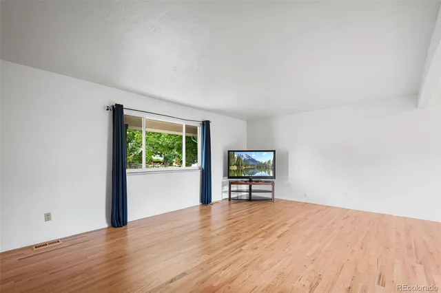 a view of a livingroom with wooden floor and a window