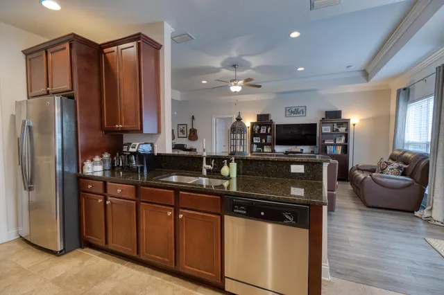 a kitchen with stainless steel appliances granite countertop a refrigerator a stove top oven a sink dishwasher and wooden cabinets with wooden floor