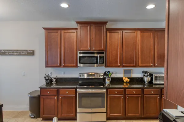 a kitchen with stainless steel appliances granite countertop a stove a sink dishwasher and a microwave oven with cabinets