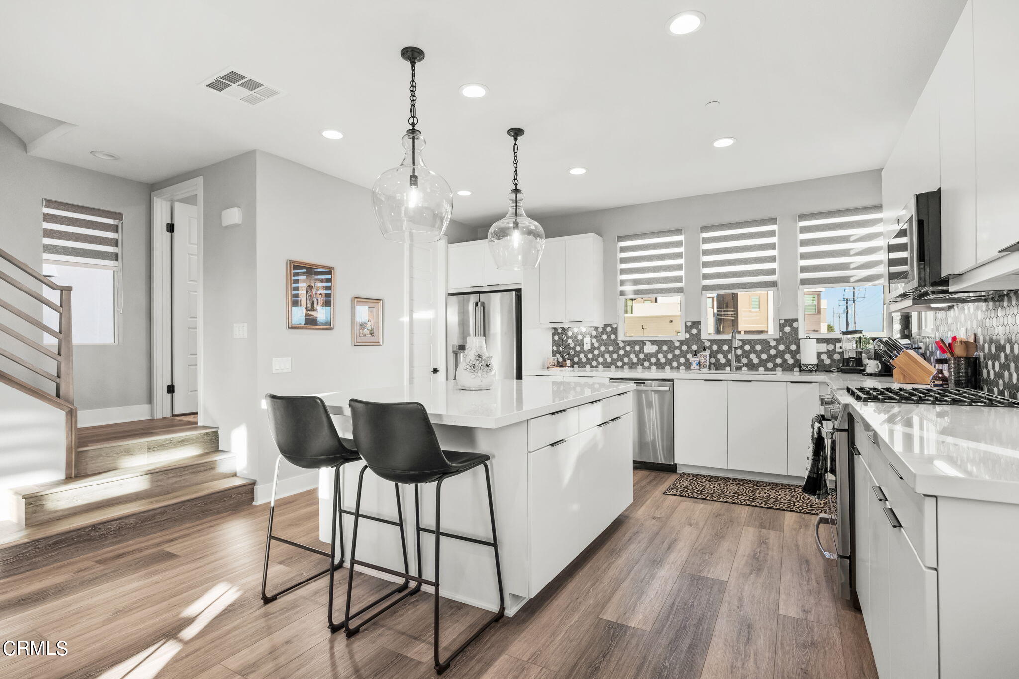 1051 Canal Street Oxnard, CA 93035 - Photo 19 of 54 a kitchen with stainless steel appliances kitchen island granite countertop a stove a sink and white cabinets with wooden floor next to windows