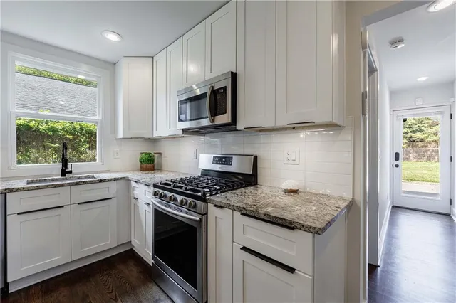 a kitchen with stainless steel appliances granite countertop a sink stove and cabinets