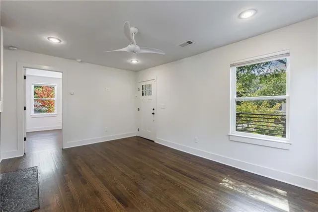 a view of an empty room with wooden floor and a window