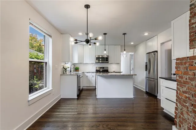 a kitchen with stainless steel appliances a refrigerator a sink dishwasher a stove and white cabinets with wooden floor