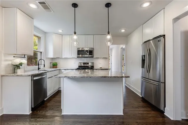 a kitchen with stainless steel appliances granite countertop white cabinets granite counter tops and a hard wood floors