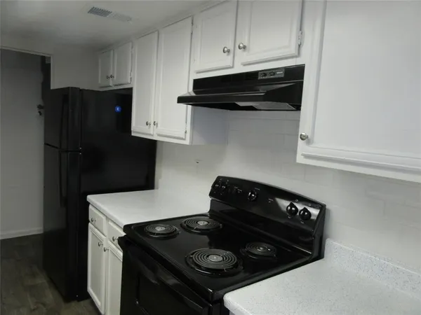 a kitchen with stainless steel appliances granite countertop white cabinets and black stove top oven with granite countertops