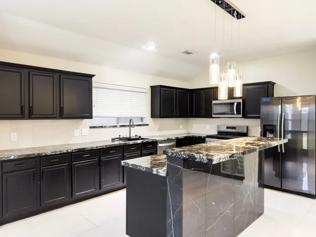 a kitchen with stainless steel appliances granite countertop a sink stove and refrigerator