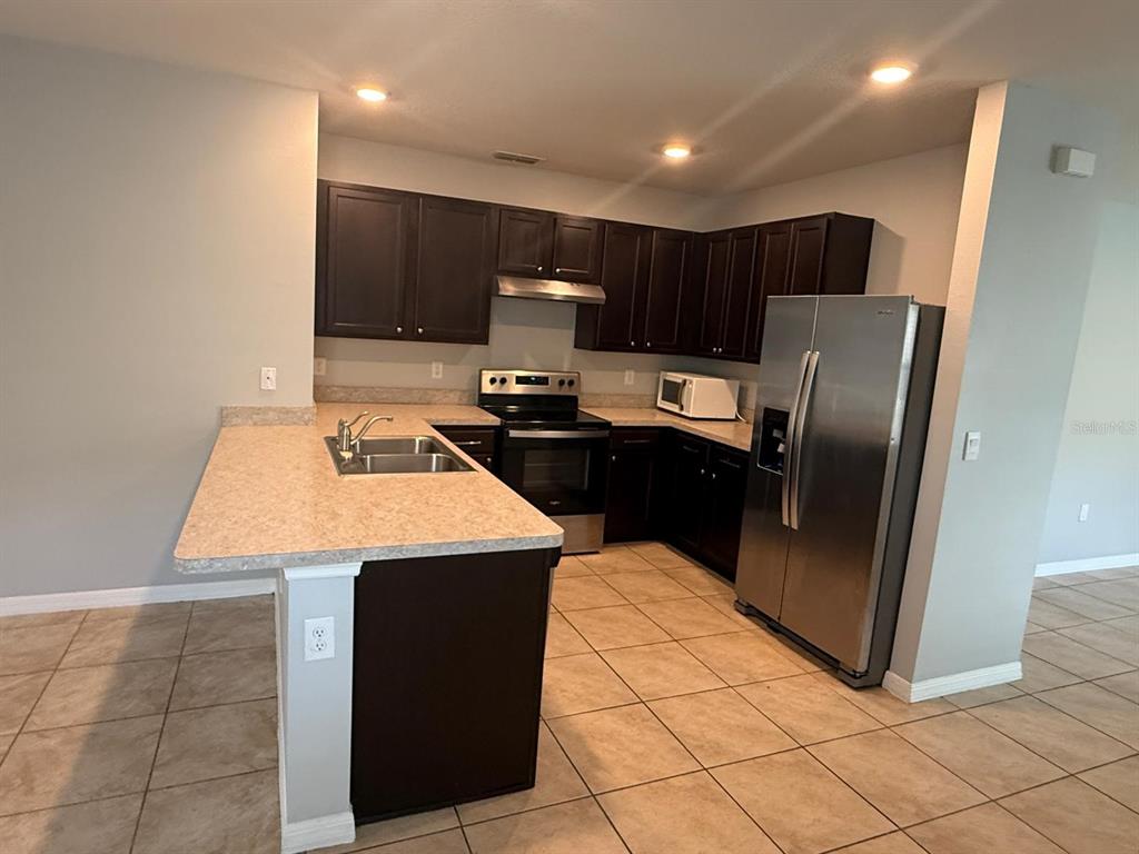 754 Chinoy Road Davenport, FL 33837 - Photo 13 of 26 a kitchen with kitchen island sink refrigerator and stove