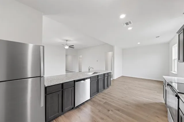 a kitchen with stainless steel appliances granite countertop a refrigerator a sink and a white cabinets