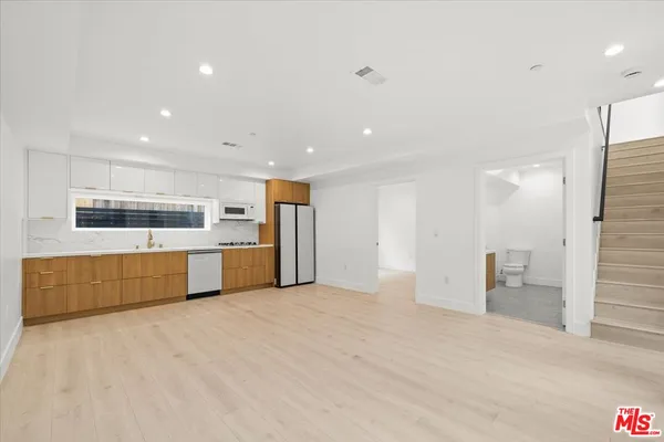 a large kitchen with stainless steel appliances a large counter top a stove and a refrigerator