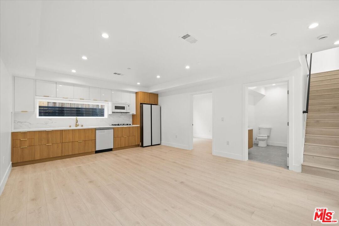 a large kitchen with stainless steel appliances a large counter top a stove and a refrigerator