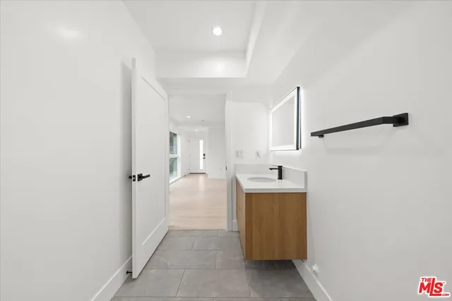 a bathroom with a sink and mirror with bathtub