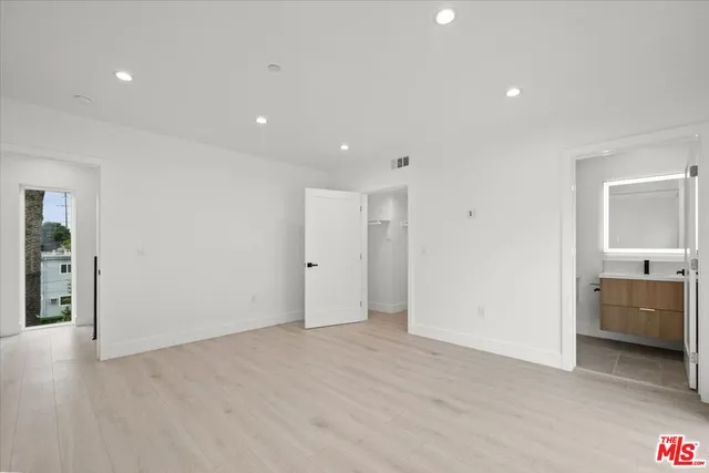a view of an empty room with closet and bathroom