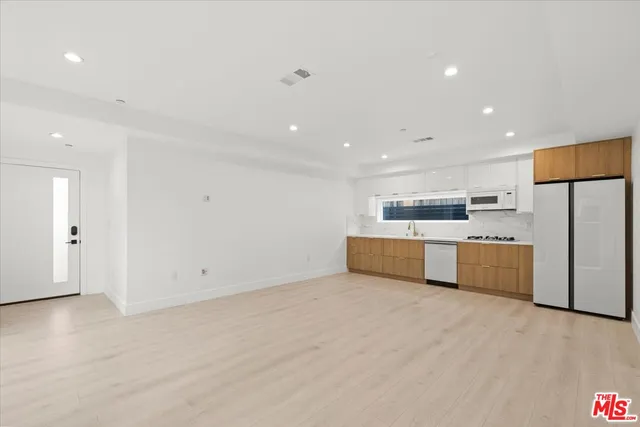 a large white kitchen with a refrigerator a stove top oven and white cabinets