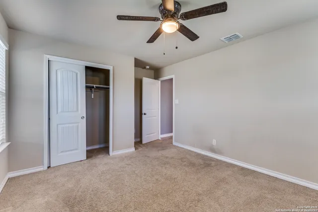an empty room with closet and a chandelier fan