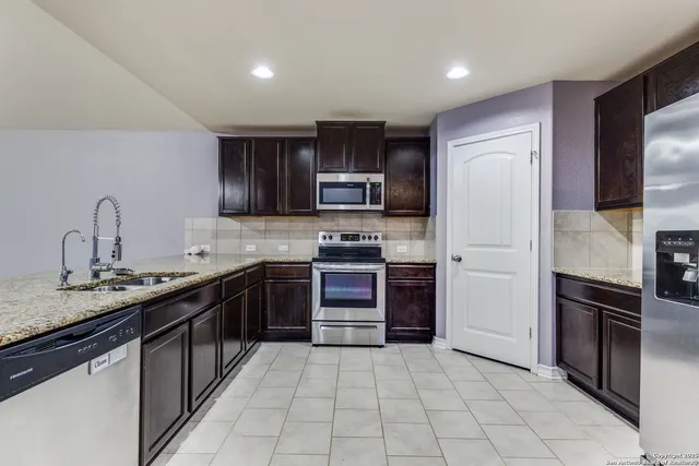 a kitchen with stainless steel appliances granite countertop a refrigerator and a stove top oven
