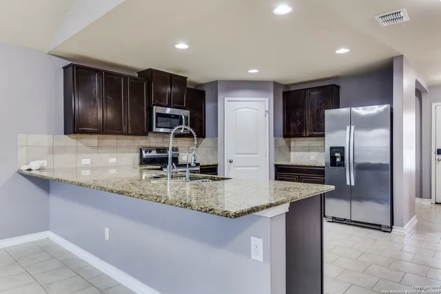 a kitchen with stainless steel appliances granite countertop a sink a stove and a refrigerator