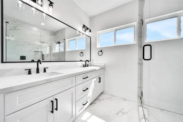 a bathroom with a double vanity sink a mirror and shower