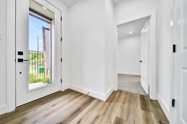 a view of a hallway with wooden floor and a bathroom