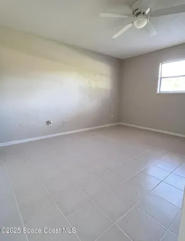 an empty room with a ceiling fan and window