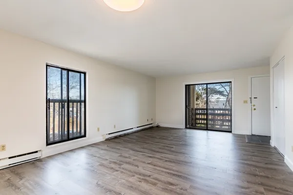 an empty room with wooden floor and windows