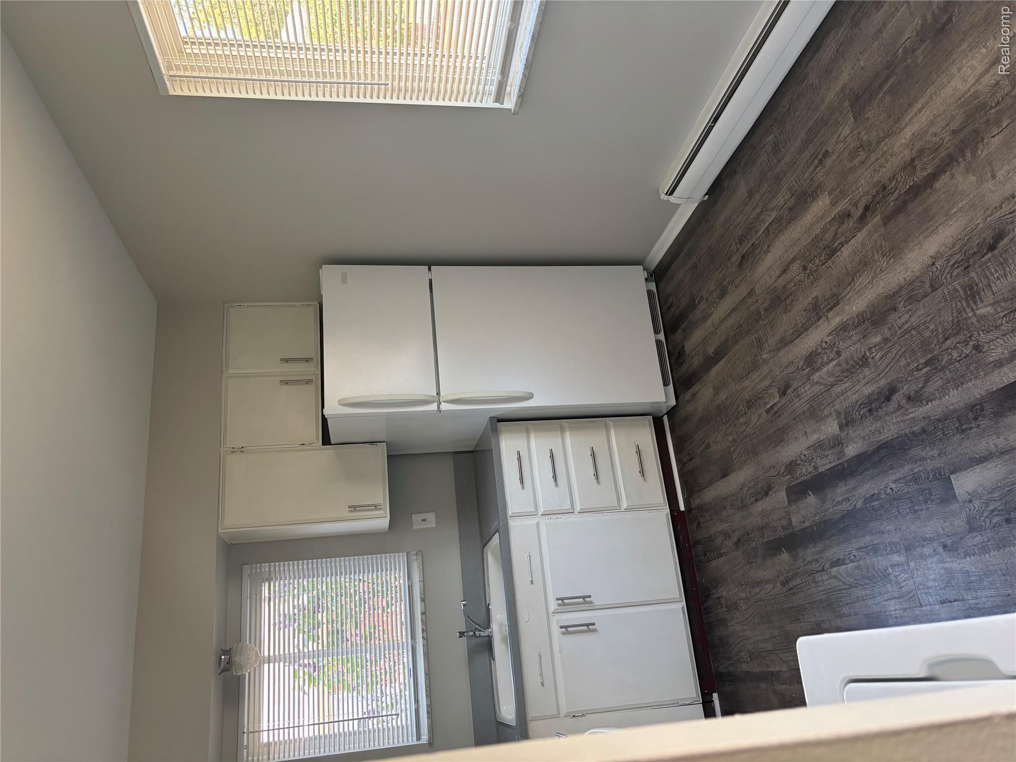22000 Beck Road, Unit 103 Northville, MI 48167 - Photo 4 of 6 Kitchen with white cabinets, a baseboard radiator, freestanding refrigerator, dark wood-style flooring, and light countertops