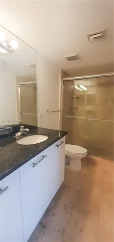 a bathroom with a granite countertop sink a toilet a mirror and shower