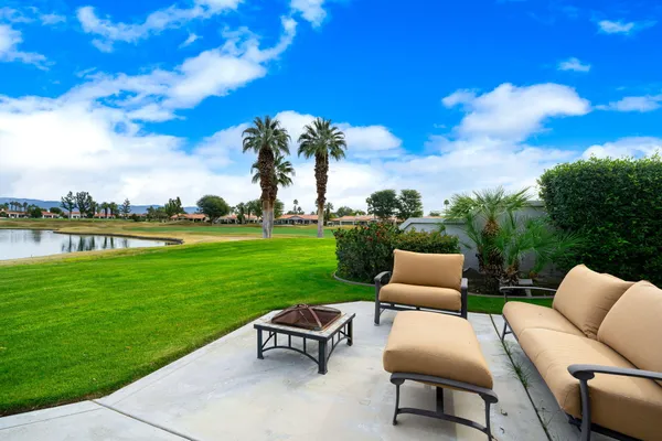 a view of a patio with couches potted plants and a big yard