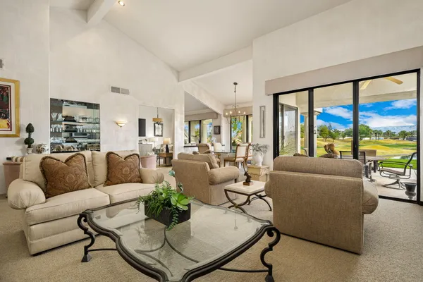 a living room with couches and kitchen view with wooden floor